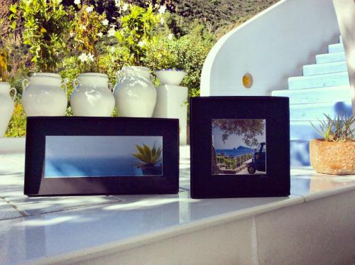 three framed pictures sitting on a table with vases at Quartara Boutique Hotel in Panarea