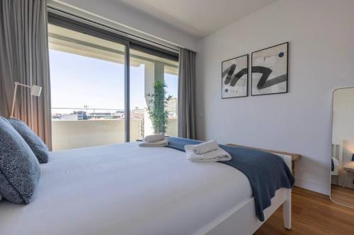 Oasis 28 III by Innkeeper في لشبونة: غرفة نوم مع سرير أبيض كبير مع نافذة كبيرة