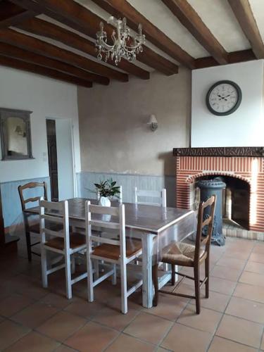 une salle à manger avec une table, des chaises et une horloge dans l'établissement Les guernouilles, à Mézières-en-Brenne