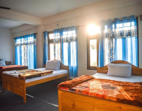 a bedroom with two beds and blue curtains at Abhinay Natural Homestay by StayApart in Gorubathān