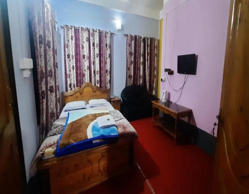 a bedroom with a bed and a table and a television at Abhinay Natural Homestay by StayApart in Gorubathān
