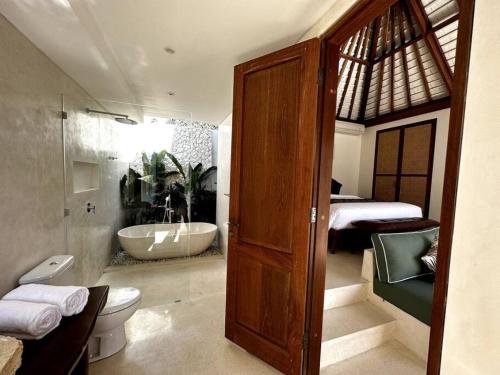 a bathroom with a tub and a toilet and a sink at Di Cappio Villa Uluwatu 4 in Uluwatu