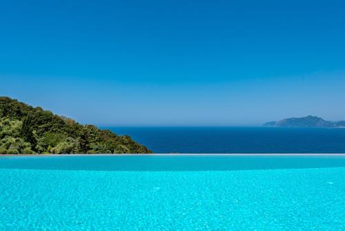 a blue swimming pool with the ocean in the background at Villa Anthelia in Pentátion