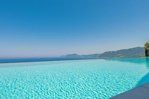 a large pool of blue water with mountains in the background at Villa Anthelia in Pentátion