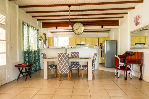 eine Küche mit einem Tisch, Stühlen und einer Uhr in der Unterkunft villa La Mérédith in Le Lamentin