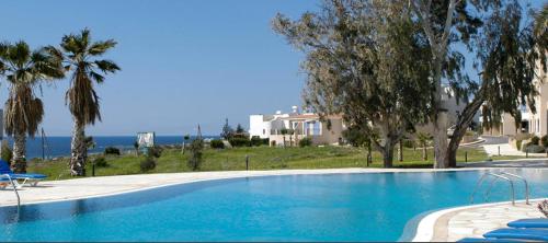 una gran piscina con palmeras y una casa en Modern and stylish 1 bedroom apartment in King's Palace en Paphos