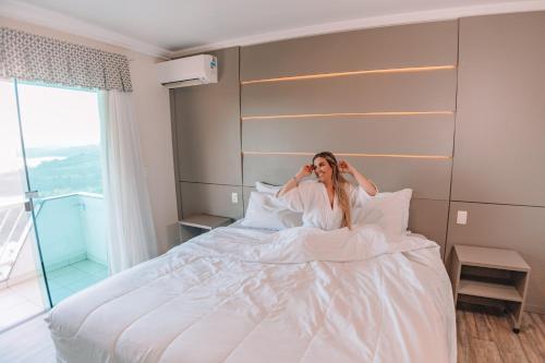 uma mulher deitada numa cama a falar ao telemóvel em Itá Thermas Resort e Spa em Itá