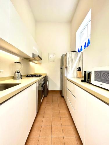 a kitchen with white cabinets and a microwave at Casa Rambla Serra Cali in Cali