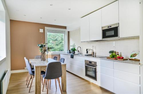 a kitchen with white cabinets and a table and chairs at Queen's Cave By Staysville in Stavanger