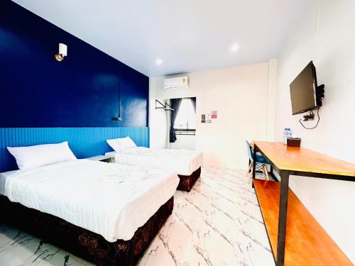 two beds in a room with a desk and a tv at Art Nara Hotel in Narathiwat
