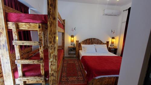 1 dormitorio con 2 literas y colcha roja en Clockwise GuestRooms, en Gjirokastra