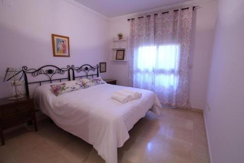une chambre avec un lit blanc et une fenêtre dans l'établissement Apartamento Los Moriscos Golf Playa Granada, à Motril