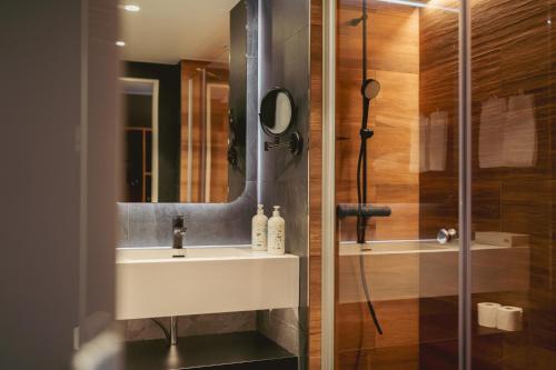 a bathroom with a sink and a shower with a mirror at Break Sokos Hotel Tahko in Tahkovuori