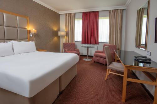 a hotel room with a large bed and a desk at Stratford Manor Hotel in Stratford-upon-Avon
