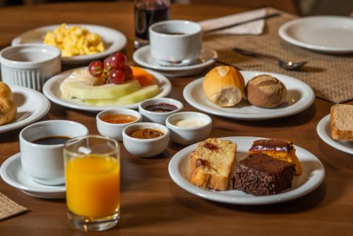 a table with plates of breakfast foods and orange juice at Hotel Laghetto Pedras Altas in Gramado