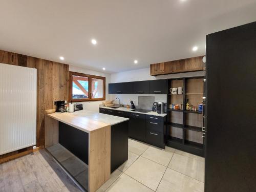 a kitchen with black cabinets and a counter top at Résidence Julianna , trajets remontées mécaniques , livraison viennoiseries, piscine couverte in Morzine