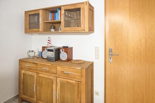 une armoire en bois avec un four micro-ondes et une porte dans l'établissement Maike, FeWo 15b, à Duhnen