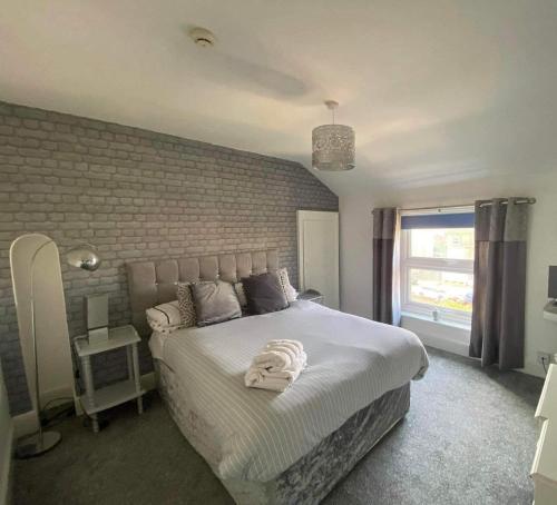a bedroom with a large white bed with a brick wall at The Beach House in Lowestoft