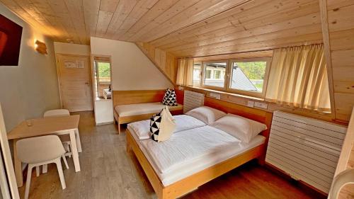 a bedroom with a bed and a table and a window at penzion a kemp Harasov in Vysoká