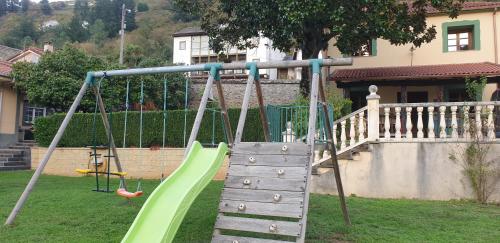 un parque infantil con un tobogán verde en un patio en Habitaciones Pumarada 2, en Cangas del Narcea