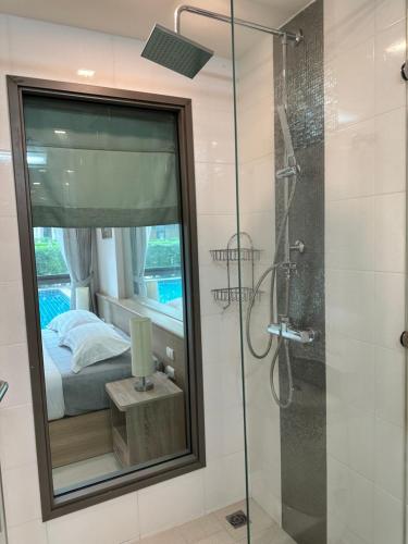 a bathroom with a glass shower and a bed at City Garden Tropicana Condo Naklua in Pattaya North
