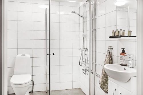a white bathroom with a toilet and a sink at Queen's Cave By Staysville in Stavanger