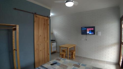 Cette chambre comprend un lit, une table et une télévision. dans l'établissement Studios da ilha praia do Francês, à Praia do Frances