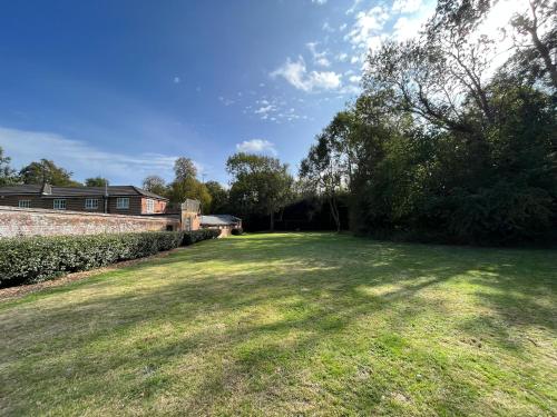 a large grassy yard with a brick wall and trees at Yu’s Guest House in Sevenoaks