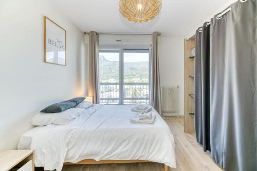 une chambre avec un grand lit et une fenêtre dans l'établissement Superbe : parking gratuit + fibre wifi + balcon, à Grenoble