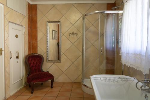 a bathroom with a shower and a chair and a tub at Mistique Waters Guesthouse in Parys