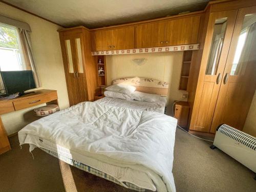 a bedroom with a bed with white sheets and a television at Caravan By The Sea At California Cliffs Holiday Park In Norfolk Ref 50014b in Great Yarmouth