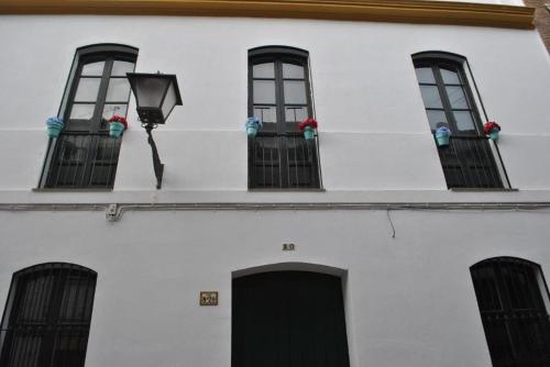 un edificio blanco con 4 ventanas y una puerta negra en TRIANA INES, en Sevilla