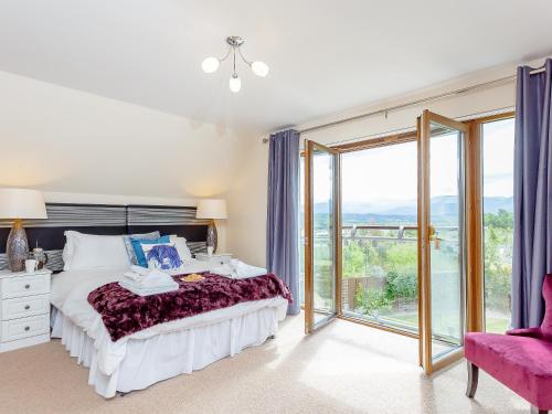 a bedroom with a bed and a large window at The Lookout in Aviemore