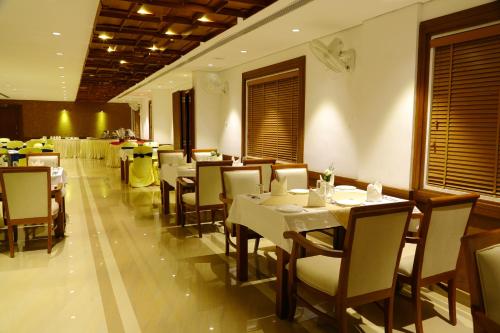 a dining room with tables and chairs in a restaurant at Vishnu Inn in Guruvāyūr