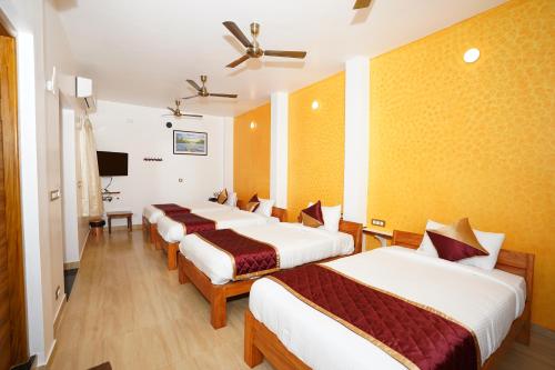 a hotel room with four beds and a television at Pearl bell Villa in Puducherry