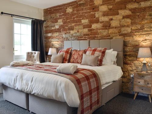 Plumbland的住宿－Holmegarth，一间卧室设有一张带砖墙的大床