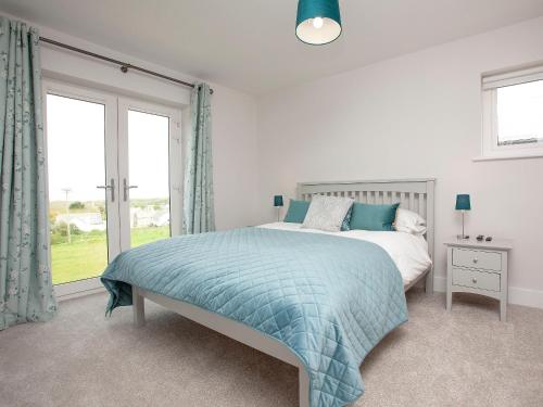 a bedroom with a bed and a large window at Fox Lodge in Crantock