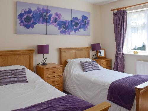 a bedroom with two beds and a painting on the wall at Cherrytree Cottage in Loftus