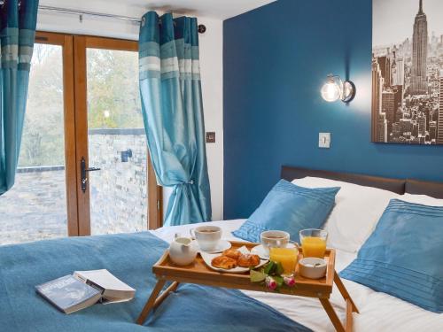 a tray of breakfast food on a bed with blue walls at Coombe Wood Coach House in Hawkinge