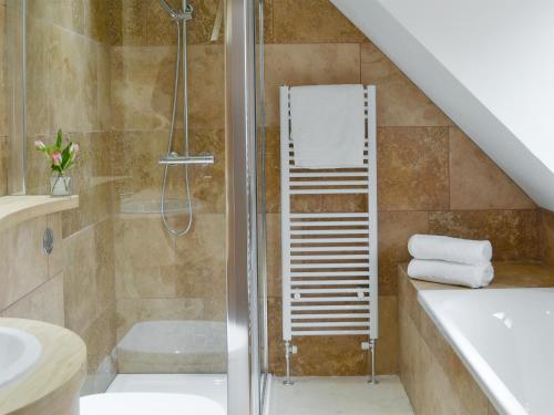 La salle de bains est pourvue d'une douche et d'une baignoire. dans l'établissement Coombe Wood Coach House, à Hawkinge