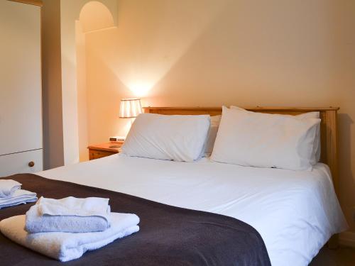 a bed with white sheets and towels on it at Birch in Llanddona