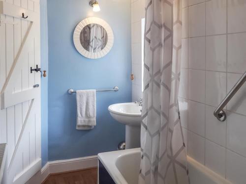 y baño con paredes azules, lavabo y bañera. en Meredith Cottage, en Dolwyddelan