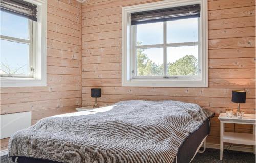 a bedroom with wooden walls and two windows and a bed at Stunning Home In Skjern With Kitchen in Lem