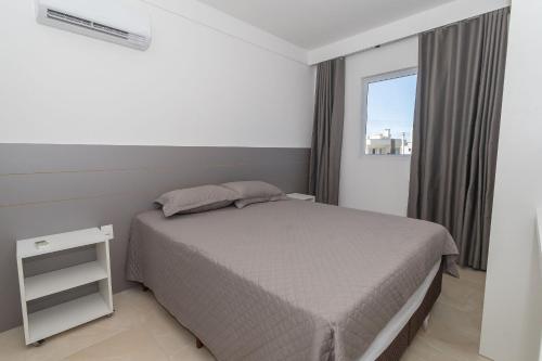 een kleine slaapkamer met een bed en een raam bij 006A - Apto novo 2 quartos em condomínio de luxo em Bombas in Bombinhas
