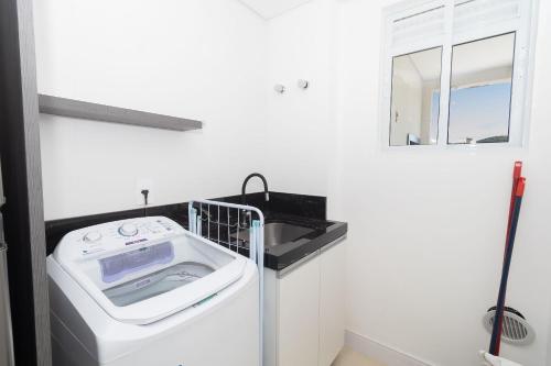 een wasmachine in een wasruimte met een spiegel bij 006A - Apto novo 2 quartos em condomínio de luxo em Bombas in Bombinhas