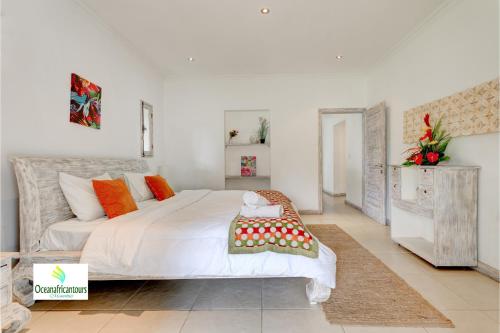 a bedroom with a large white bed with orange accents at Oasis 1 Villa Tropicale in Grand Baie