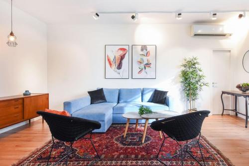 a living room with a blue couch and a table at Charming 2BR by HolyGuest in Tel Aviv