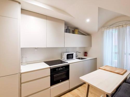 una pequeña cocina con armarios blancos y una mesa en Zarautz Bella Suite by Aston Rentals en Zarautz