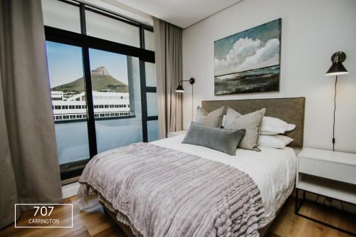 1 dormitorio con cama y ventana grande en The Carrington Top Floor Luxury Apartment, en Ciudad del Cabo
