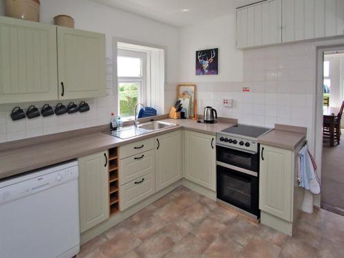 a kitchen with white cabinets and a sink at Dunmaghlas in Pirnmill